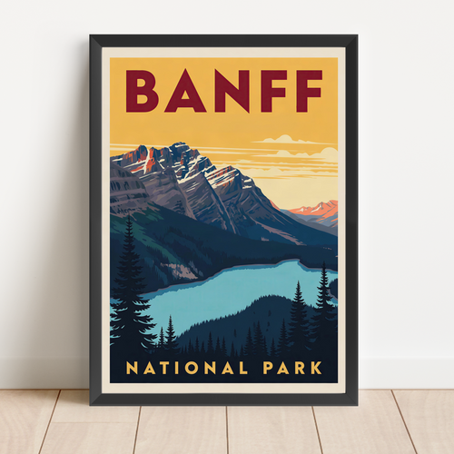 A framed vintage-style travel poster for Banff National Park leaning against a white wall on a light wood floor. The poster features a mountain landscape with a blue lake, dark pine trees, and bold text reading 'BANFF' at the top and 'NATIONAL PARK' at the bottom.